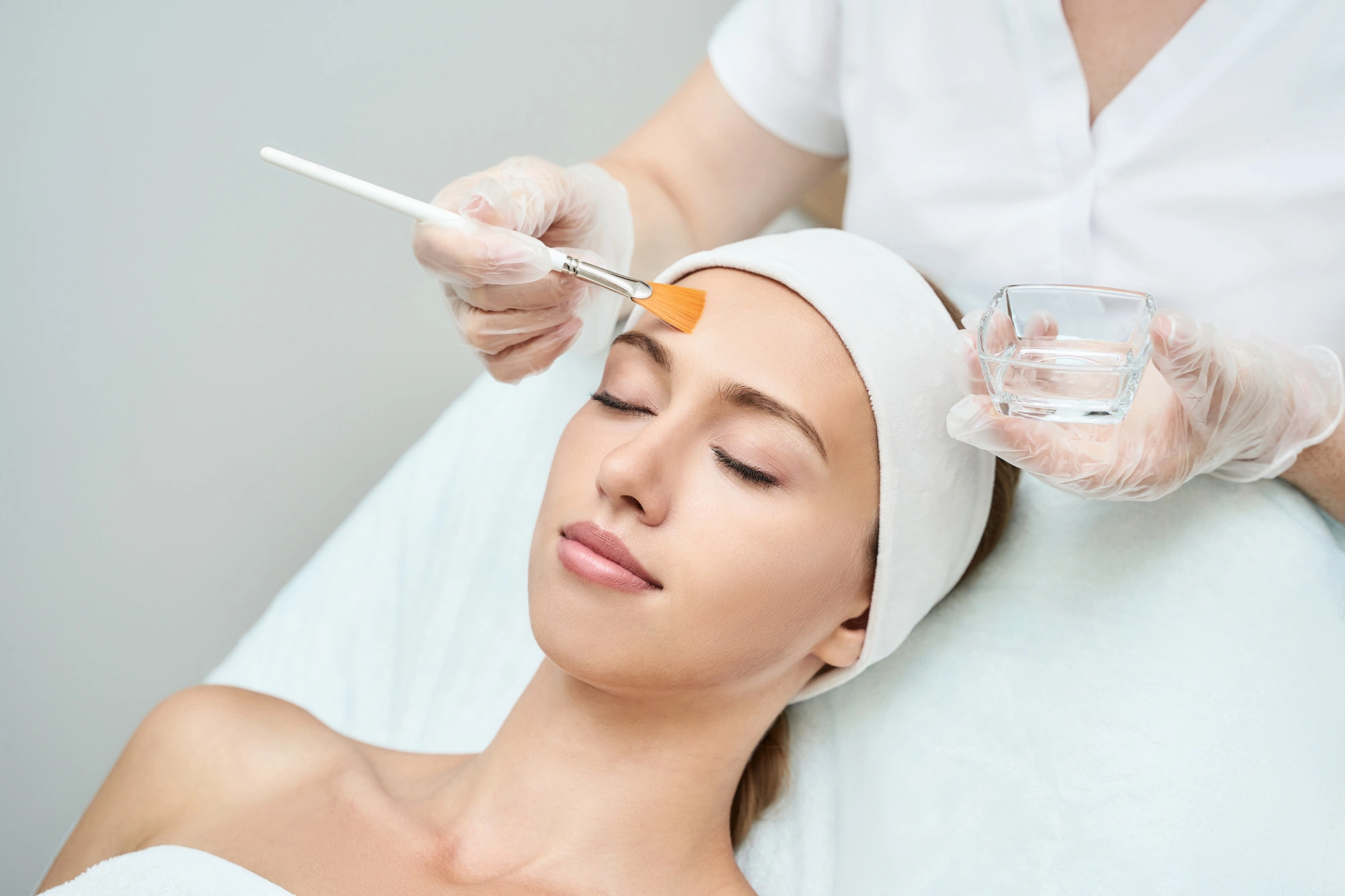 Beautician applying peels on the young female face in Sycamore, IL | Nuvo Aesthetics Clinic