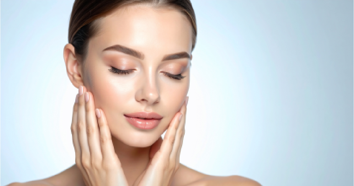 Woman with clear glowing skin touching face showing facial rejuvenation results in Sycamore, IL | Nuvo Aesthetics Clinic